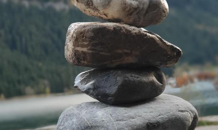 Pierres empilées devant un lac de montagne – petits pas, grand effet