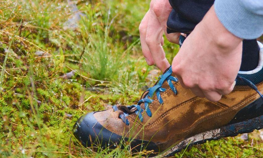 Hiker tying hiking boots on a meadow
