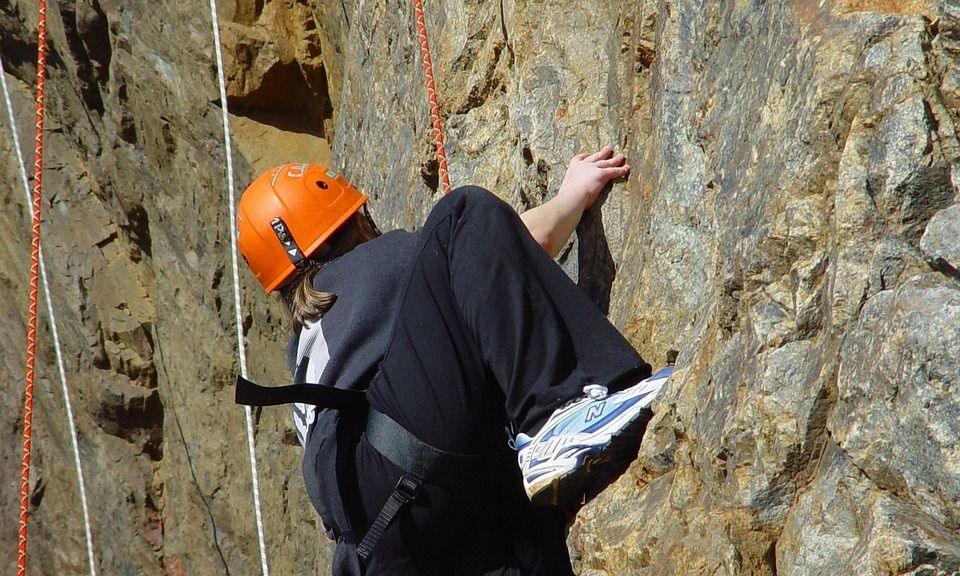 Grimpeur au casque orange sur une paroi rocheuse