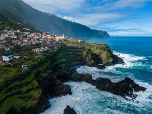 a scenic view of a village on a cliff by the ocean